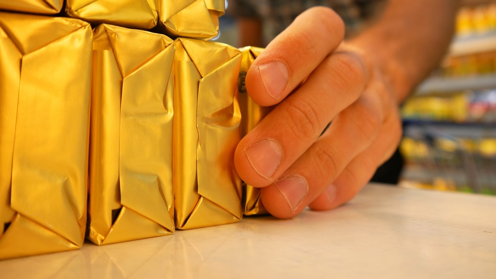 Close-up of butter packagings on a supermarket fridge shelf and a male buyer's hand takes one