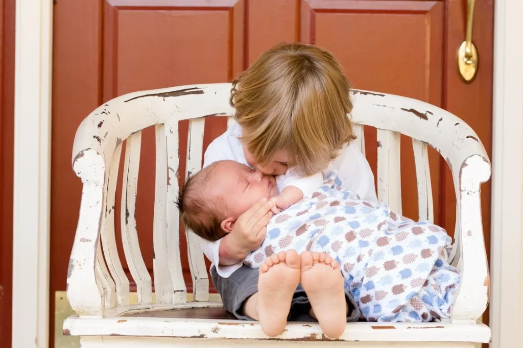 small boy cradling baby on a wooden chair