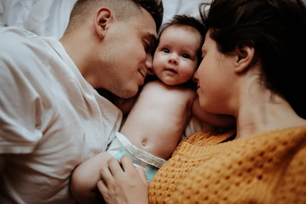 couple cradling baby between them on bed
