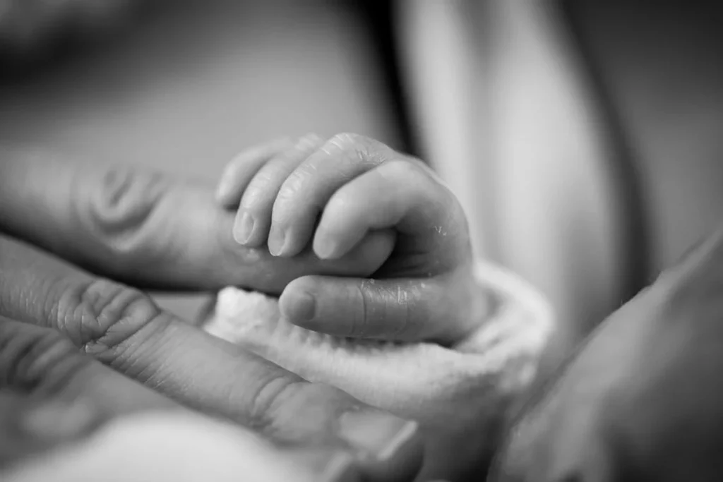 surrogate baby's hand gripping onto mother's finger
