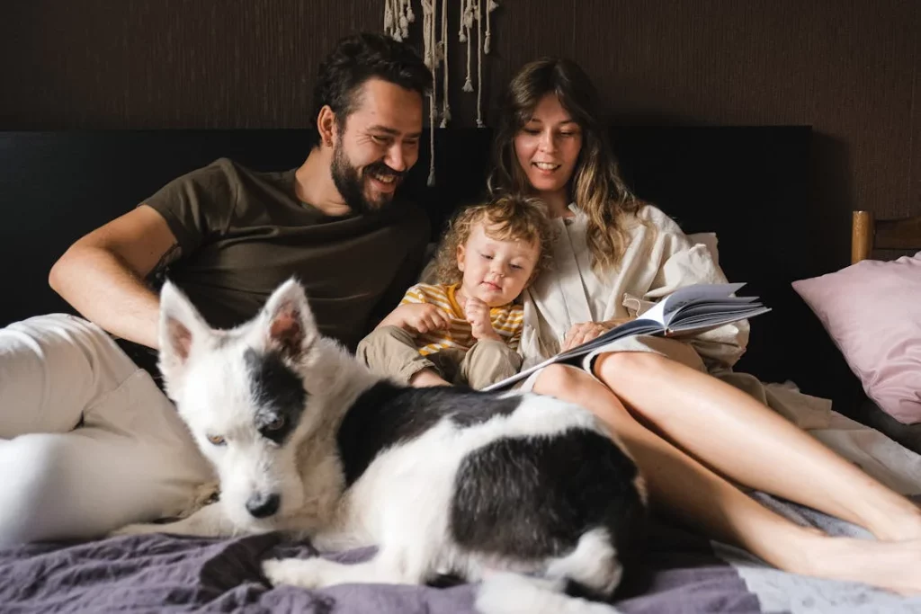happy family reading book on bed with dog
