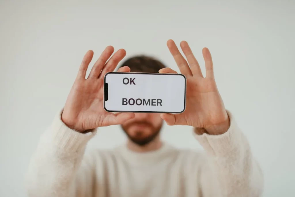 man holding cellphone up with the words 'ok boomer'