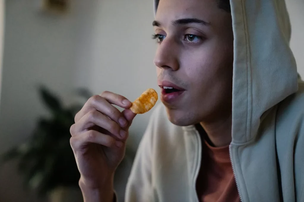 ethnic man with potato chip at home