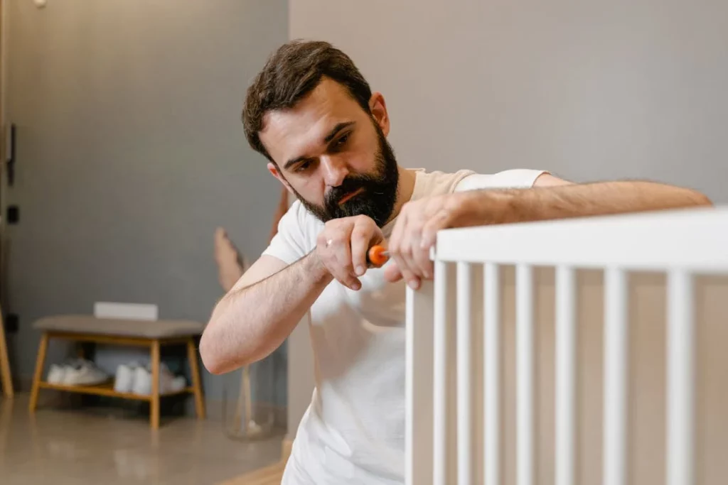 man putting together a baby cot