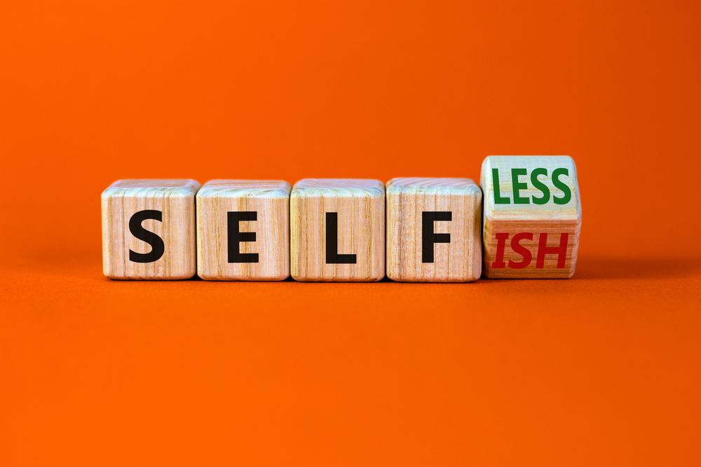 Selfish or selfless symbol. Turned cubes and changed the word 'selfish' to 'selfless'. Beautiful orange background, copy space. Business, psuchological and selfish or selfless concept.
