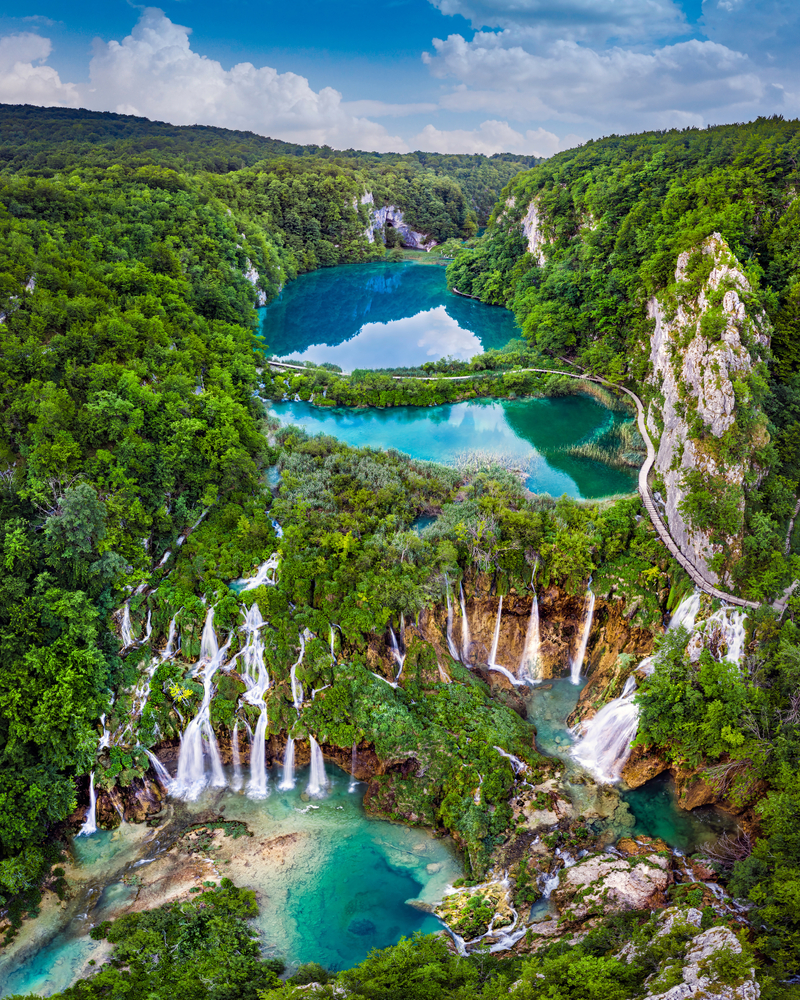 Plitvice, Croatia - Panoramic view of the beautiful waterfalls of Plitvice Lakes in Plitvice National Park on a bright summer day with blue sky and clouds and green foliage and turquoise water