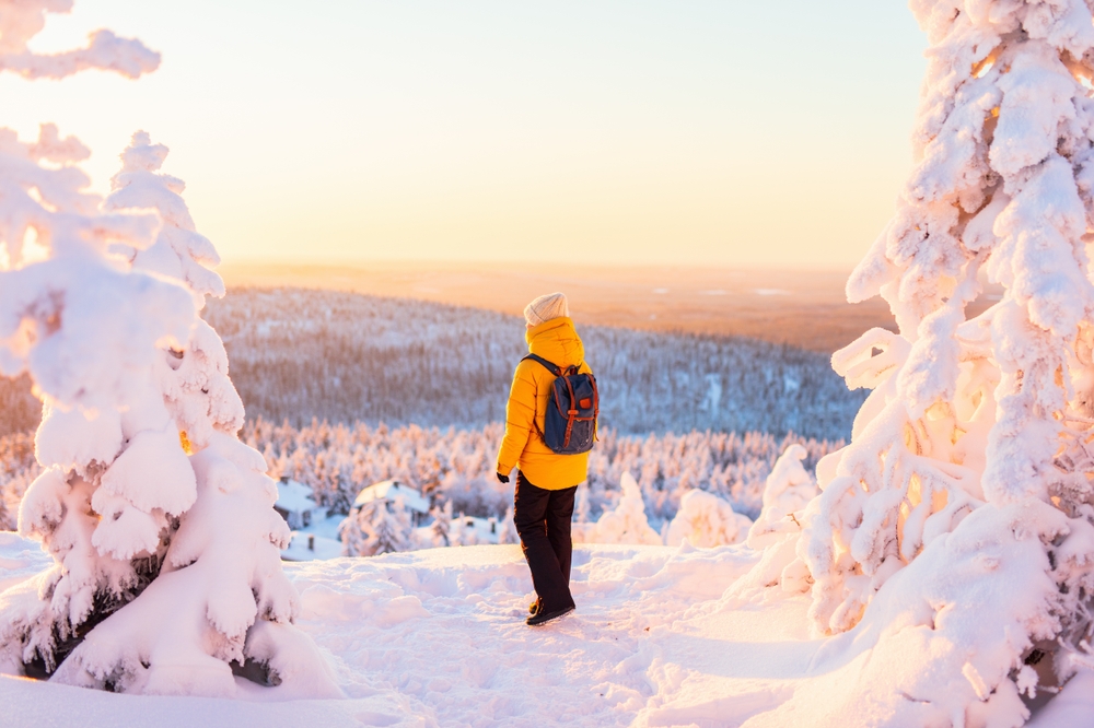 Young woman enjoying stunning view over winter forest with snow covered trees in Lapland Finland