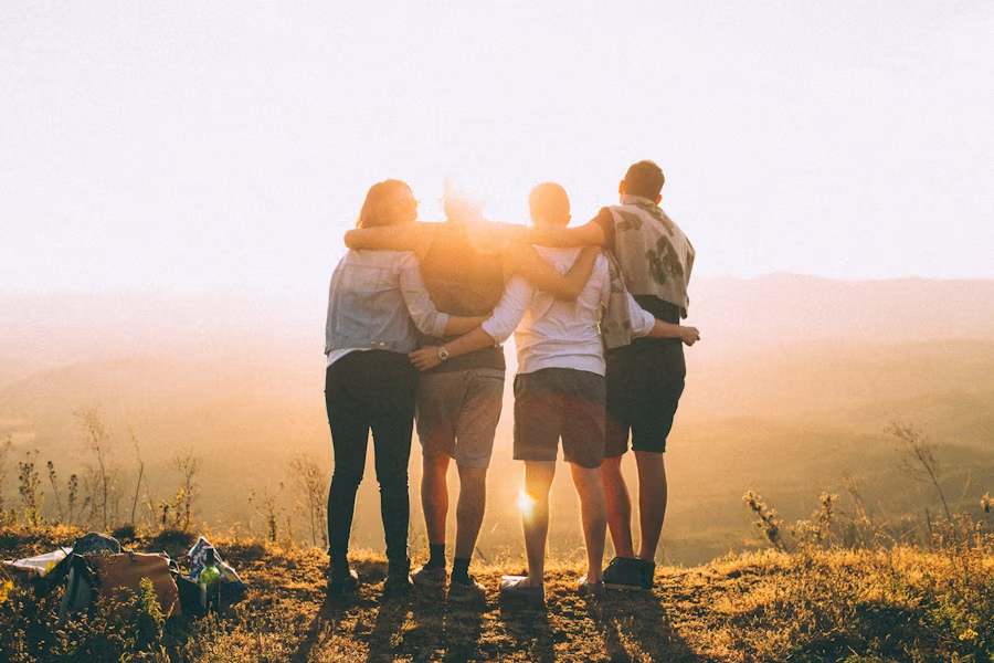 a group of friends holding each other as the sun sets