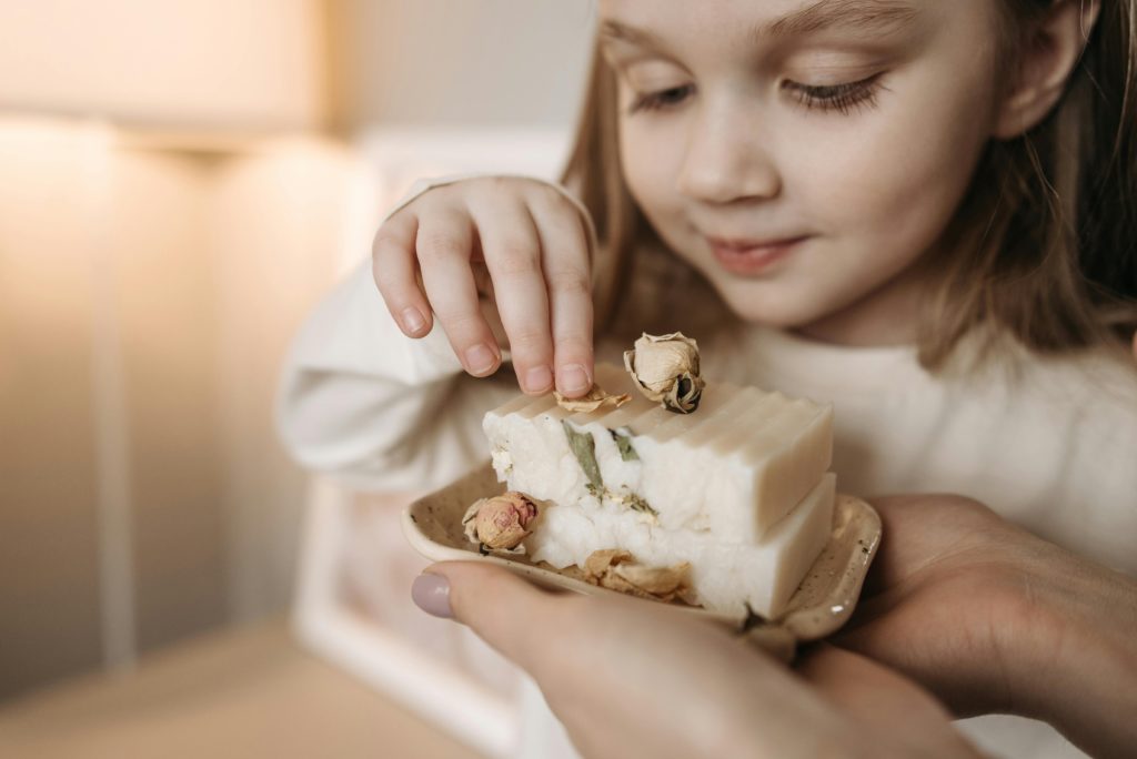 A Child Touching Bars of Soap in a Dish