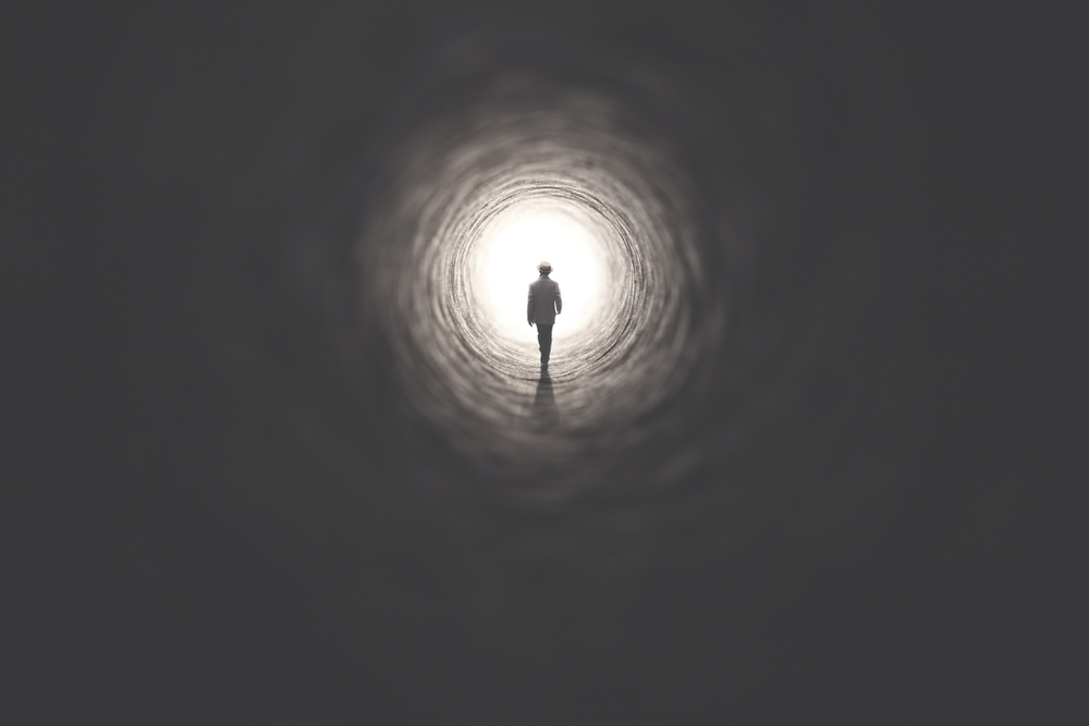 man getting out of a dark tunnel toward light
