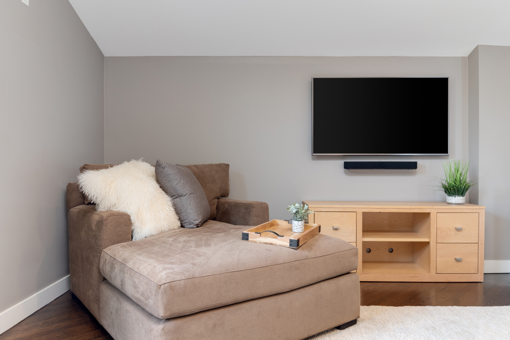A detail shot of a relaxing sitting area with a blank television on the wall and a little tray with a plant on top.