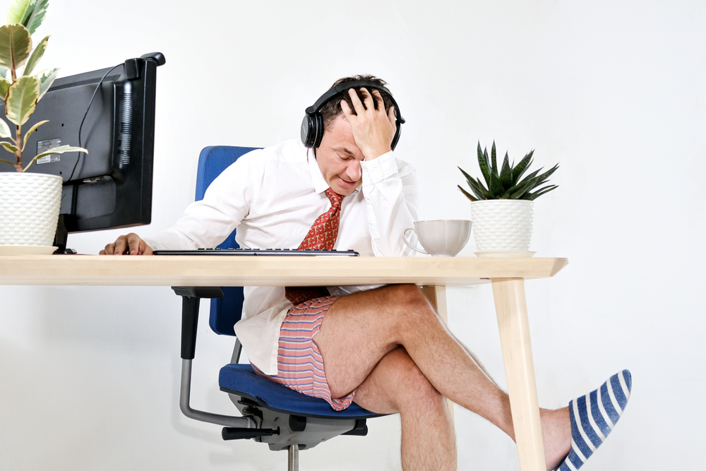 The male manager works remotely at home, holds online meetings. He is experiencing is tired and embarrassed. He is wearing a shirt and tie, underpants and slippers. Stay home and quarantine
