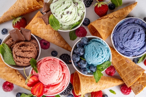 Colorful bright ice cream on bowls, with waffle cones and berries, on white background. Variety of ice cream portions with different flavor with fresh berries top view copy space layout background