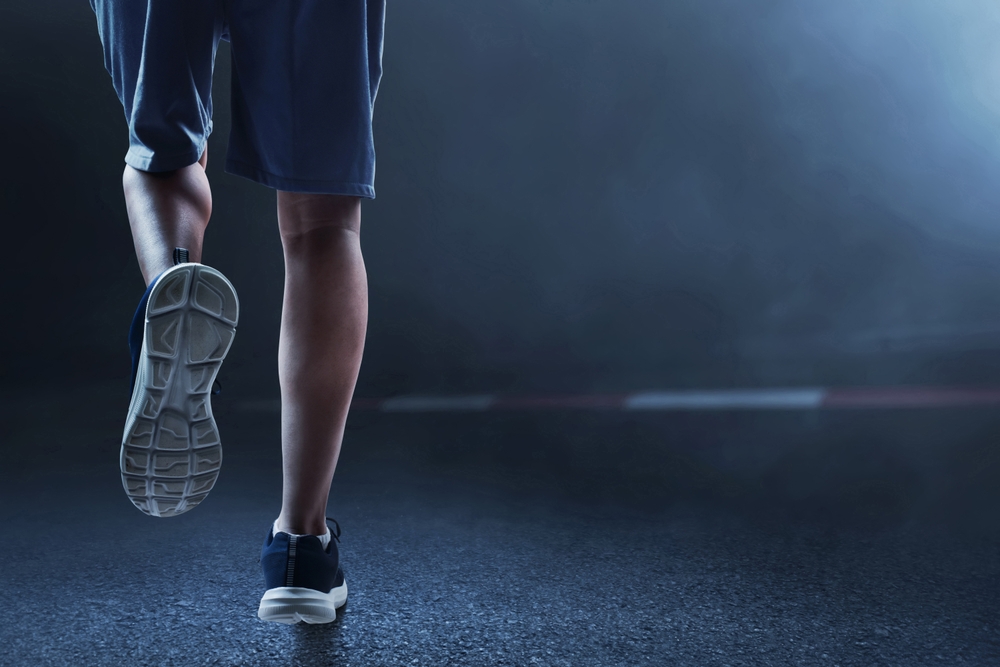 Young man legs running on the street at dark night with smoke
