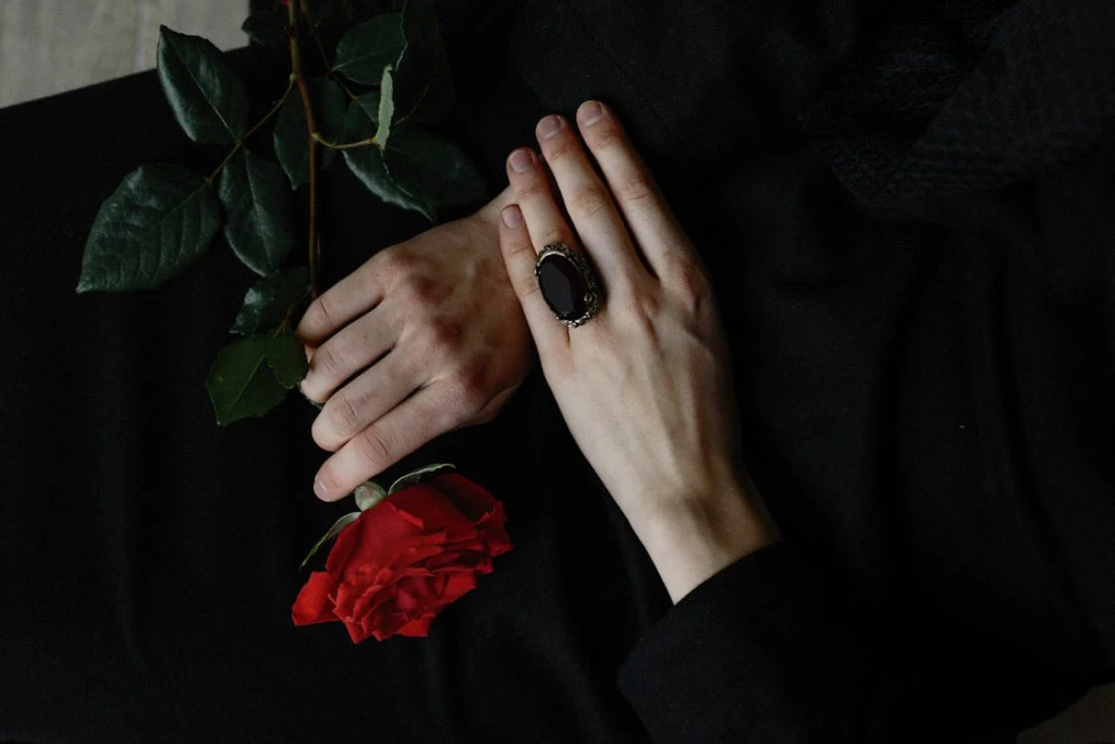 person laying with red rose in hand