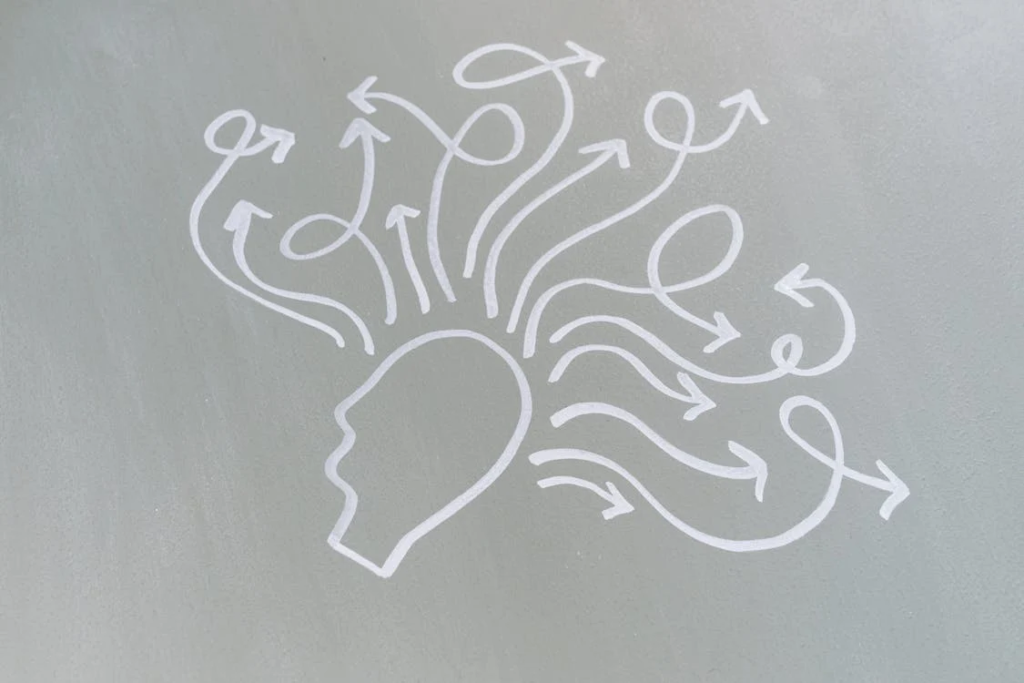 A simple white line drawing on a light gray background depicting a human head in profile with multiple curving arrows streaming outward from it. The arrows point in different directions, representing thoughts, ideas, or information flowing from the mind. The minimalist design suggests concept sharing, brainstorming, or mental processes.