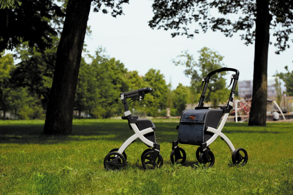 A modern white walker or rollator mobility aid sitting on grass in a park, representing the Medicare benefits for mobility equipment that helps seniors maintain independence and quality of life.