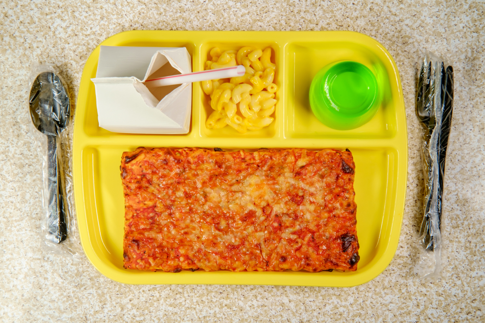 Grade school lunch tray with pizza with small carton of milk mac-n-cheese and green gelatin for dessert