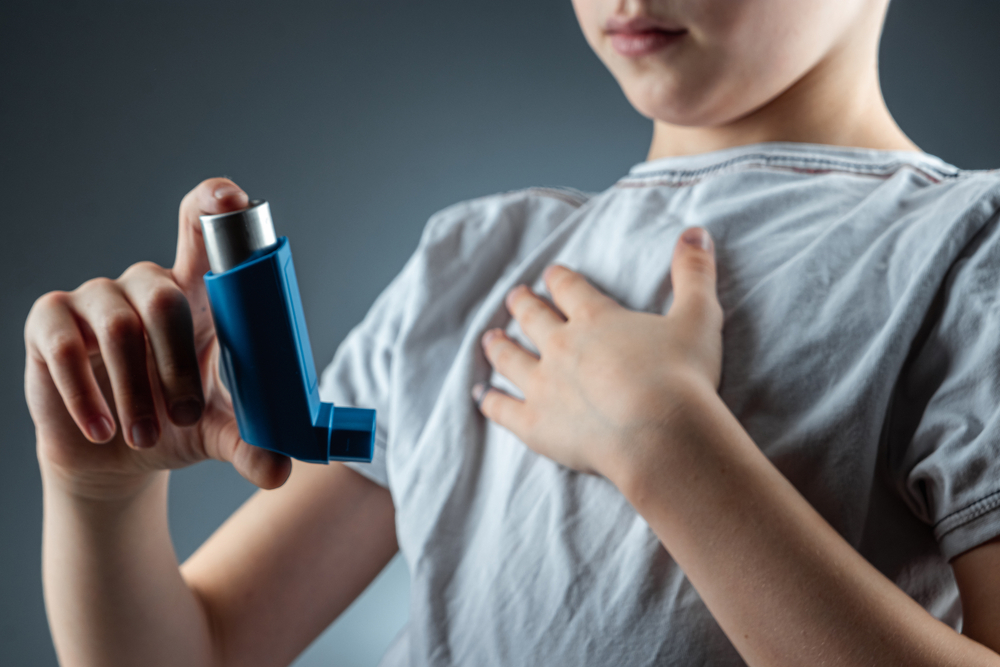 The boy holds an asthma inhaler in his hands to treat inflammatory diseases, shortness of breath. The concept of treatment for cough, allergies, respiratory tract disease