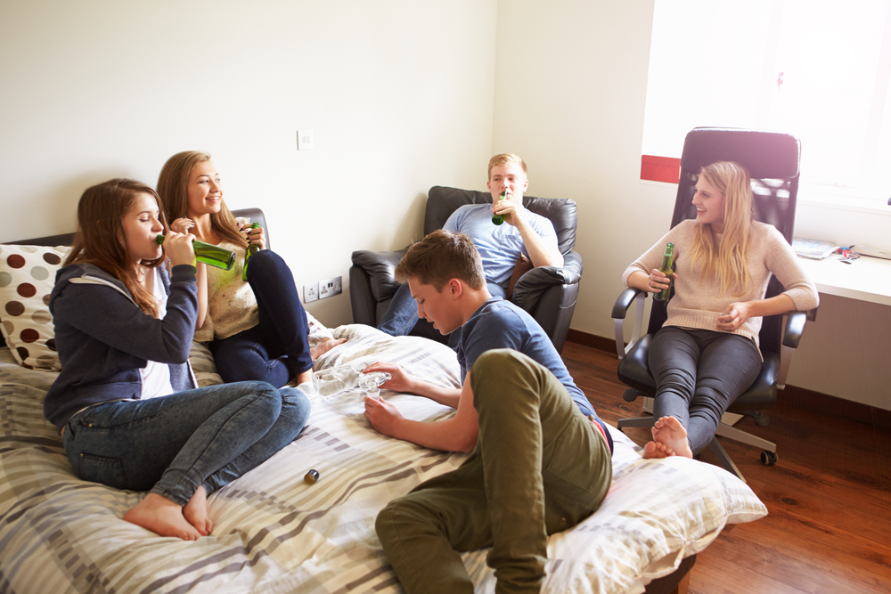 Group Of Teenagers Drinking Alcohol In Bedroom