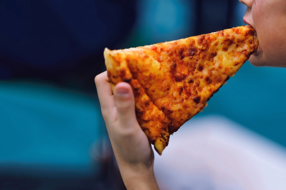 Close up of Kid boy eating slice of cheese pizza. Child eating unhealthy food, junk food, fast food, diet, nutrition and school lunch background.