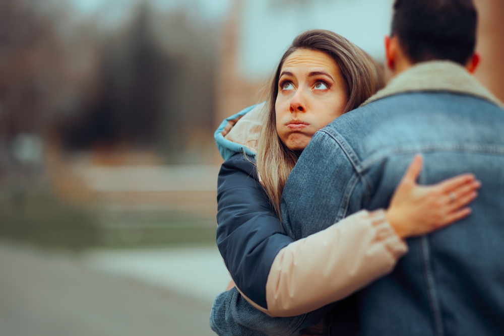 Insincere Girlfriend Hugging her Boyfriend on a Date. Bored woman keeping a guy in the friend zone giving him false hope
