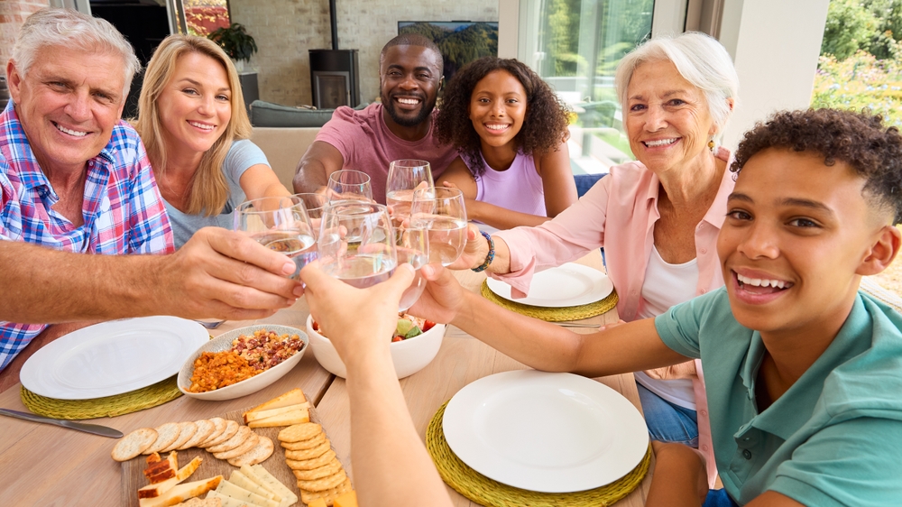 Portrait Of Three Generation Family Indoors At Home Doing Cheers With Water Before Eating Meal