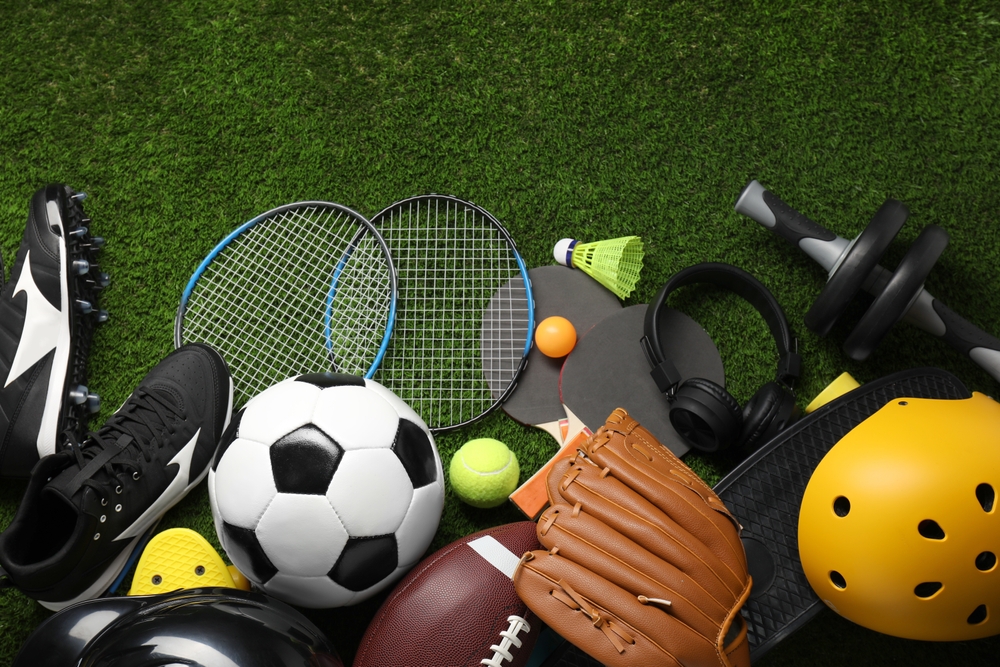Different sports equipment on green grass, flat lay
