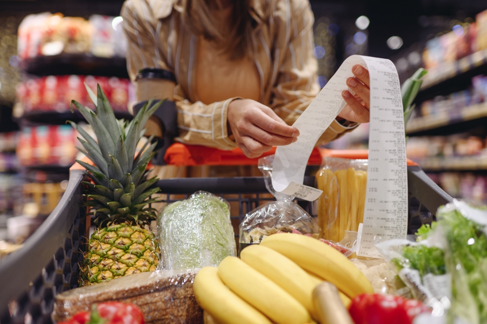 Cropped young customer woman wear casual clothes read check bill shopping at supermaket store grocery shop buying with trolley cart choose products in hypermarket. Purchasing food gastronomy concept
