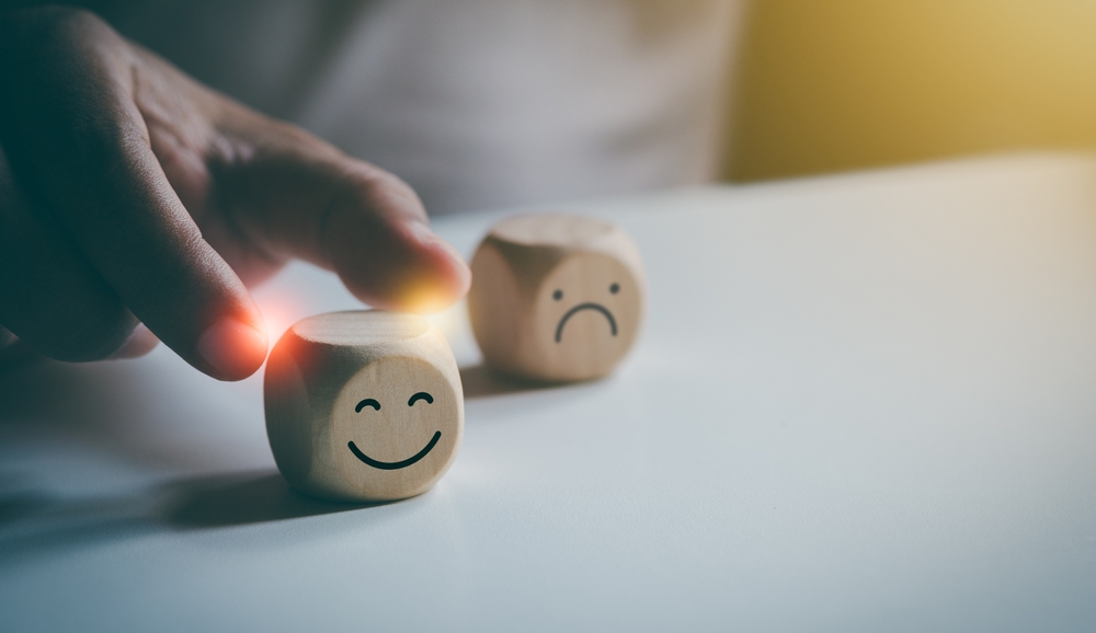 Hand holding happy smile face, Positive thinking, Wood cube with smile icon, Mental health assessment, World mental health day concept