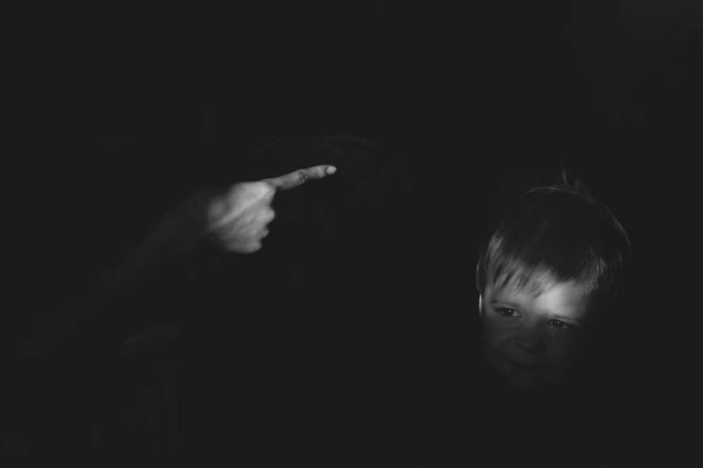 Silhouette of a child in shadow with an adult hand pointing, illustrating the psychological impact of abandonment that affects hundreds of thousands of American children annually.