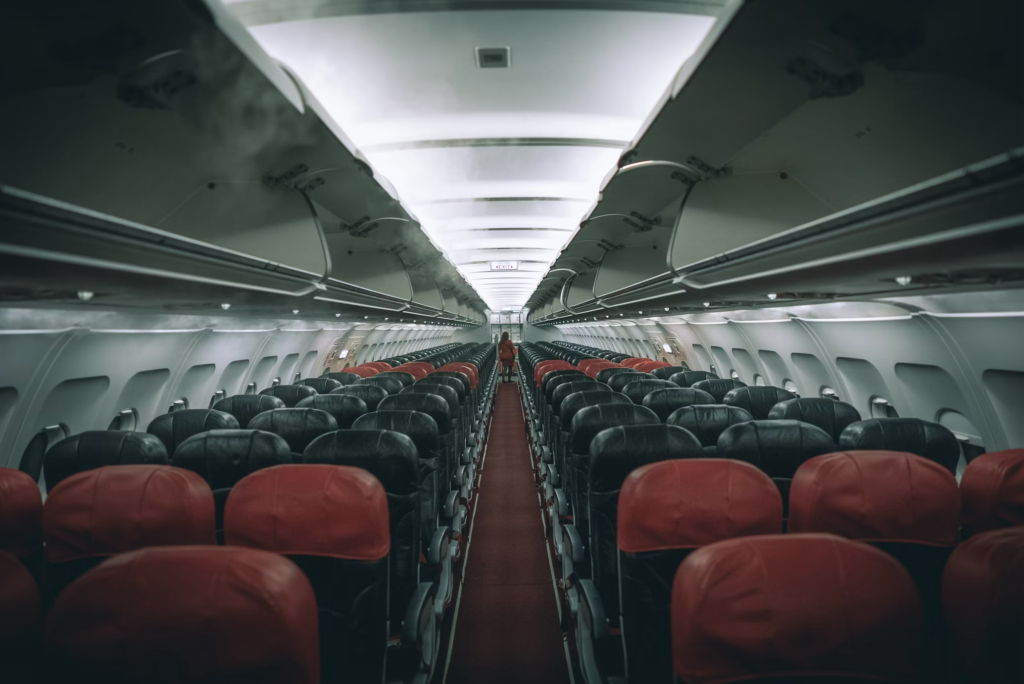 Interior view of an empty commercial airplane cabin showing rows of black and red seats, including window seats, along a center aisle. The perspective creates depth, highlighting the importance of seat selection, particularly coveted window seats that were central to the controversy.