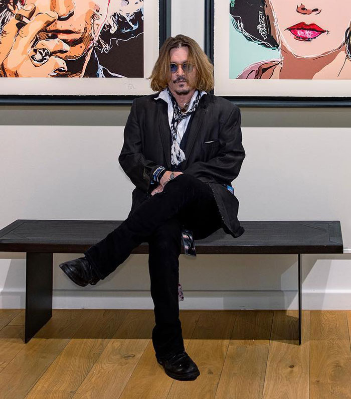 Johnny Depp seated in front of art pieces