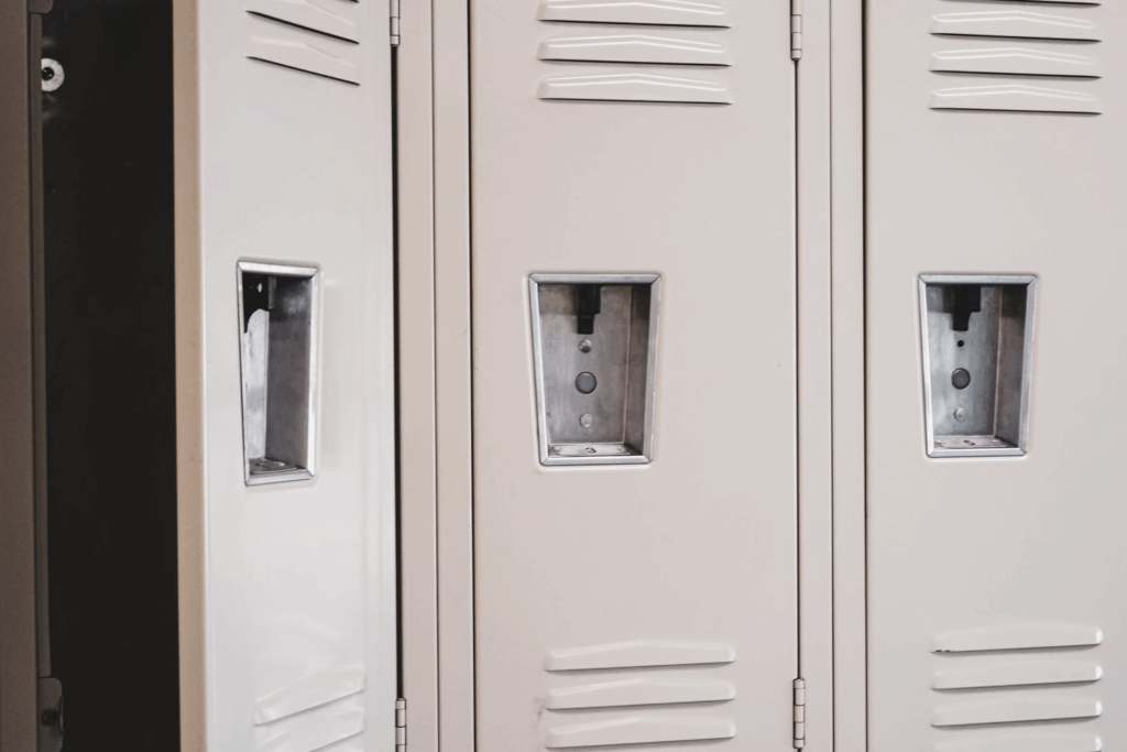 Row of white school lockers with metal vents and recessed handles, representing the high school setting where real-life incidents connected to the novel 'Rage' occurred.