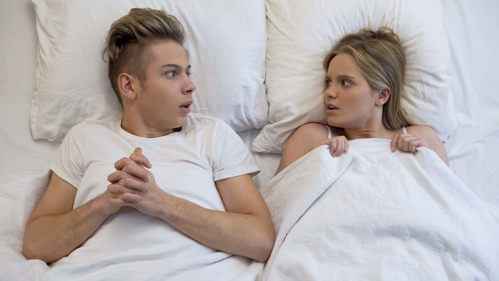 Young couple looking shocked before first experience bed, lack of sex education