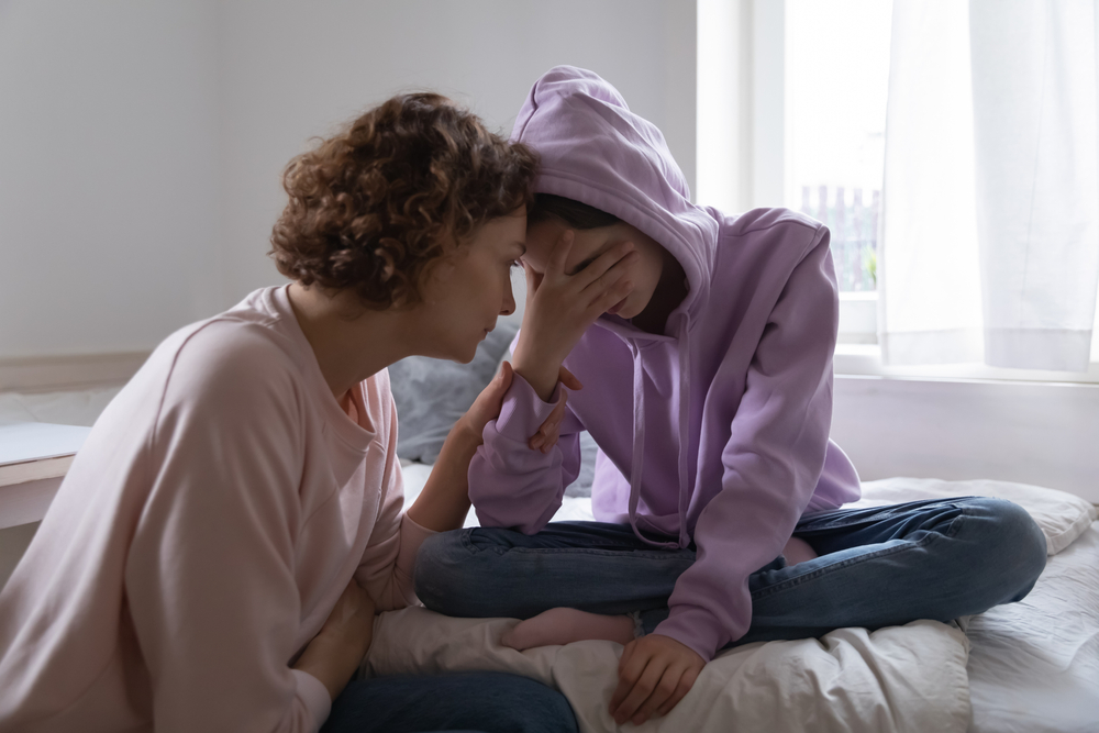 Worried parent young mom comforting depressed crying teen daughter bonding at home. Loving understanding mother apologizing or supporting sad teenage girl having psychological puberty problem concept.