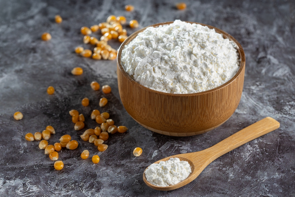 Maize starch. Cornstarch in the bowl and corn kernels.