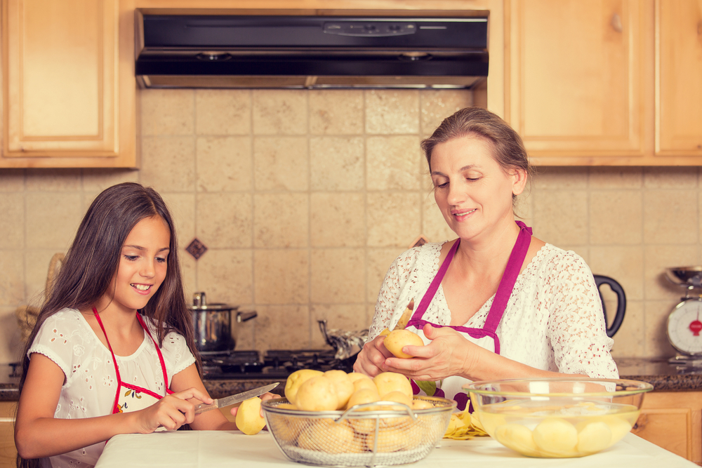 Portrait of happy, smiling mother and daughter cooking dinner, preparing food isolated background home kitchen. Positive family emotions, face expression, life perception. Healthy eating concept