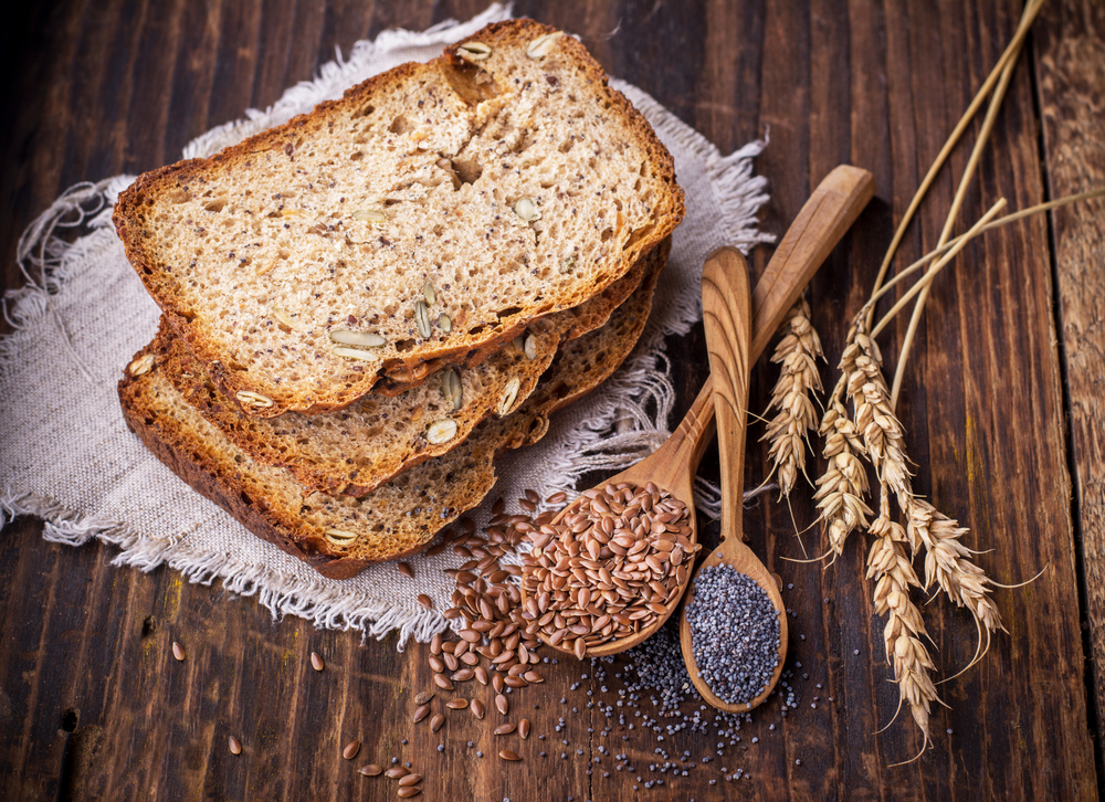 Slices of homemade dark fragrant fresh bread with poppy seeds, flax, sunflower and pumpkin on dark wooden background. The concept of home baking. selective Focus