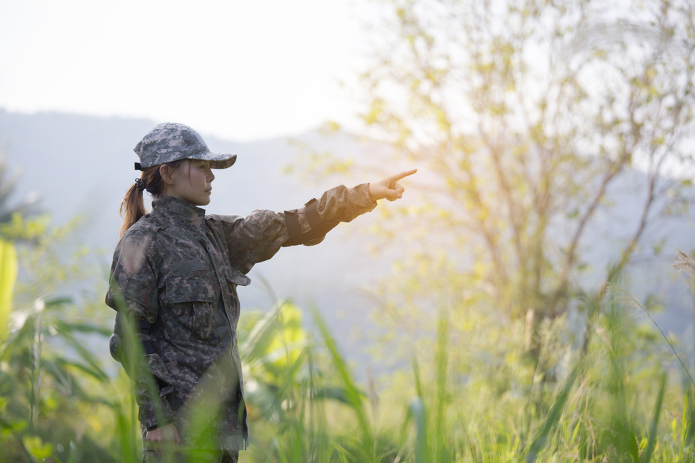 Soldier woman in Korean army uniform point her finger to jungle