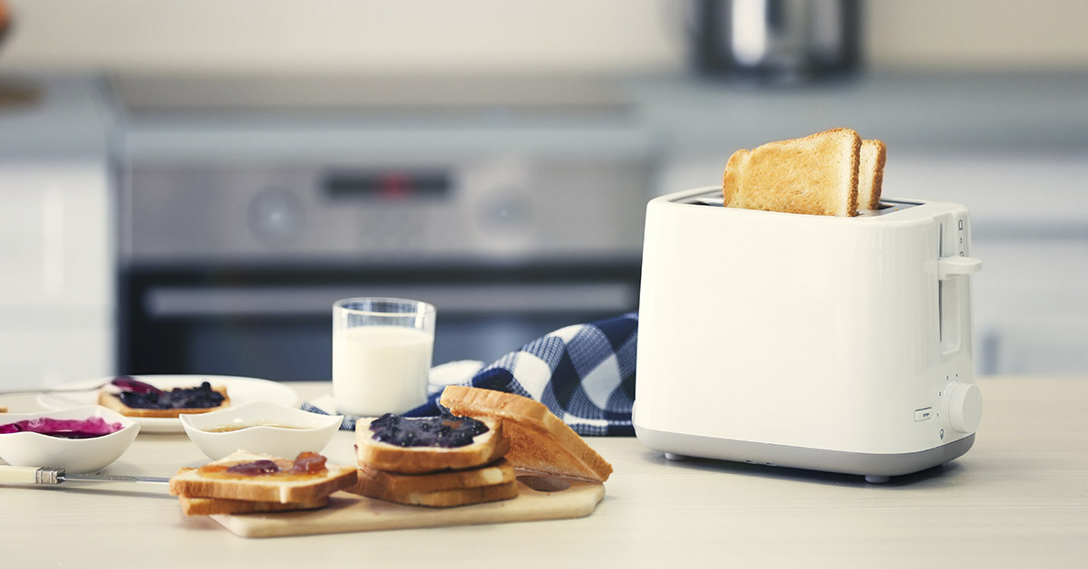 Toaster with dishes and sandwiches on a light kitchen table