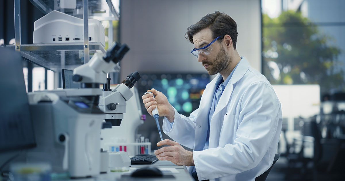 Pharmaceutical Laboratory: Young Male Scientist Working with Samples, Using Micro Pipette for Mixing Chemicals and Acids. Advanced Scientific Specialist Working with Modern Digital Microscope