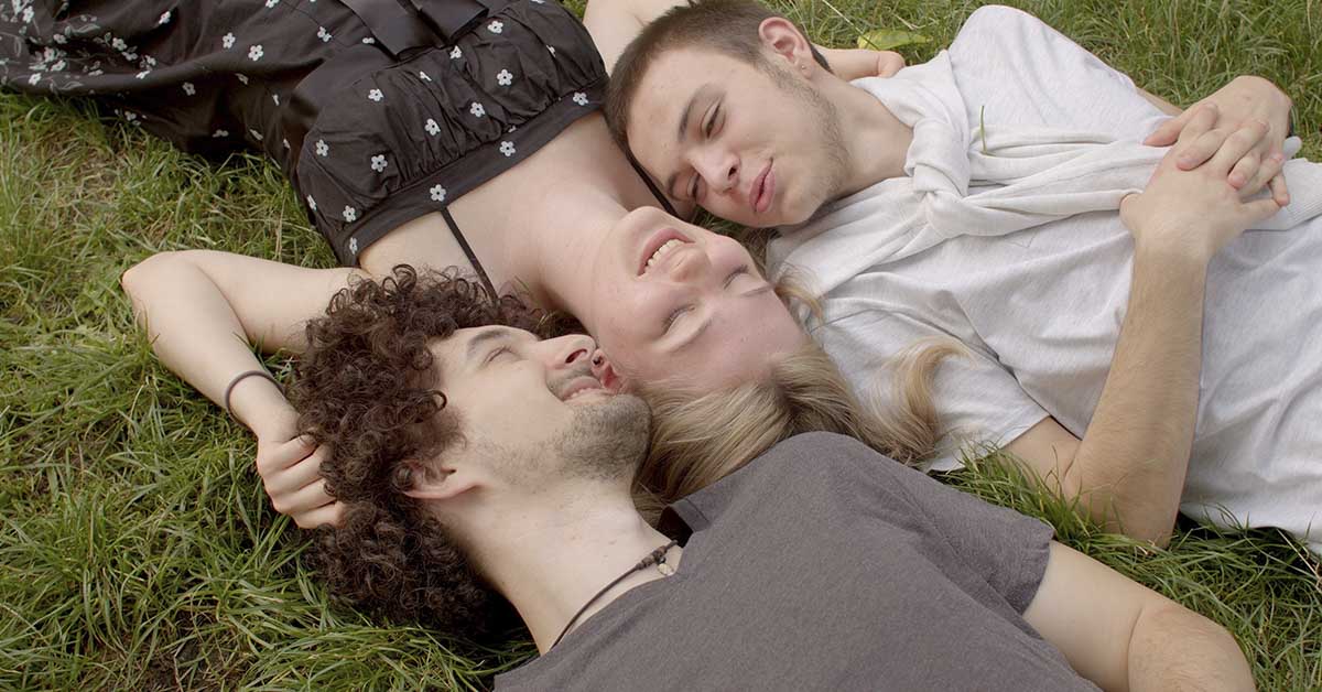 Woman laying in grass with two men. Anti Monogamy concept, polyamorous concept