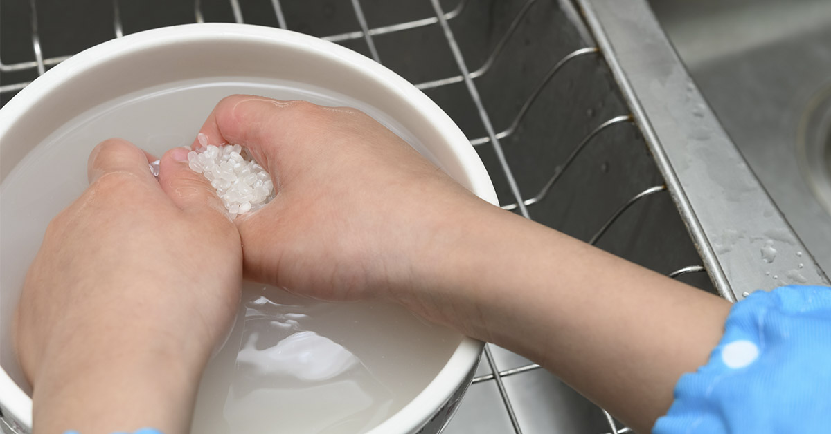 child washing rice with hands in kitchen