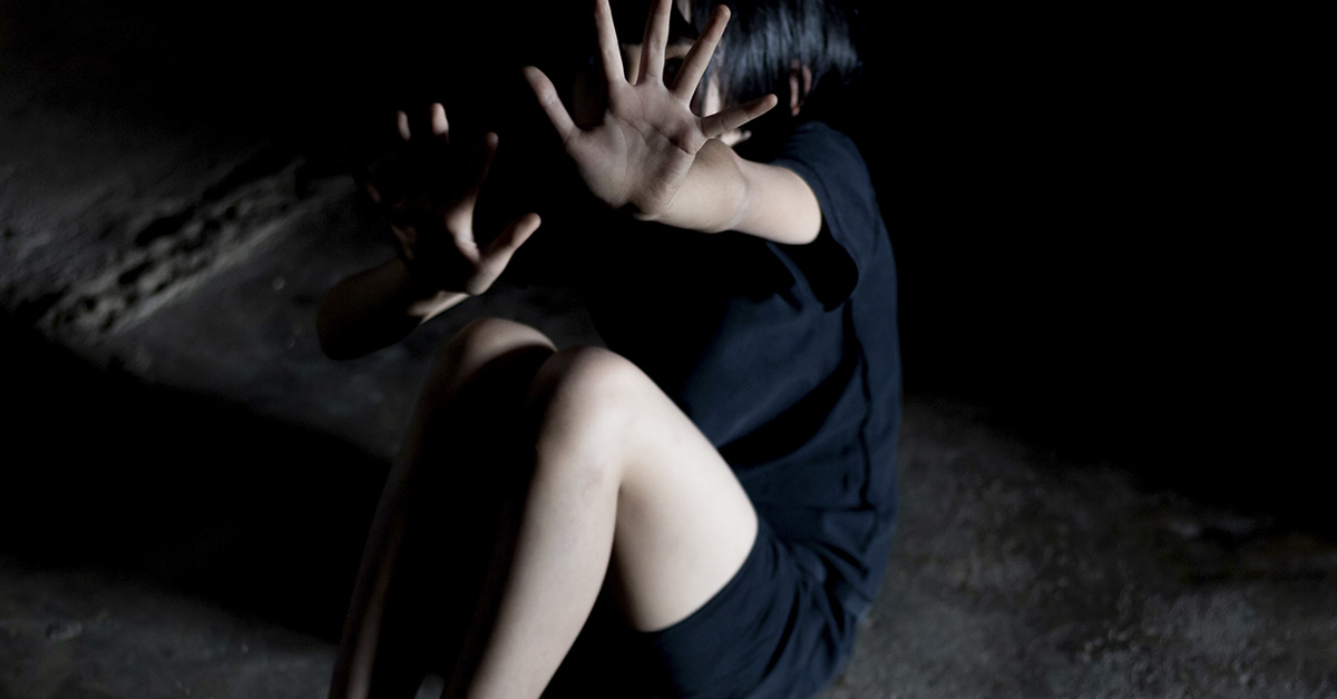 scared women placing hands in front of her fending off attacker