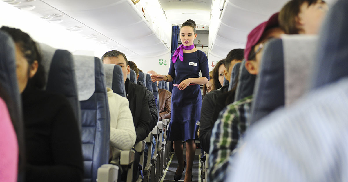 Flight attendant standing in aisle on airplane