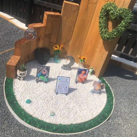 Joshua's memorial garden created by his family, with his photos surrounded by sunflowers, small decorations, and a heart-shaped wreath. This touching tribute honors his memory while serving as a painful reminder of the dangers of helium balloons that took his young life too soon.