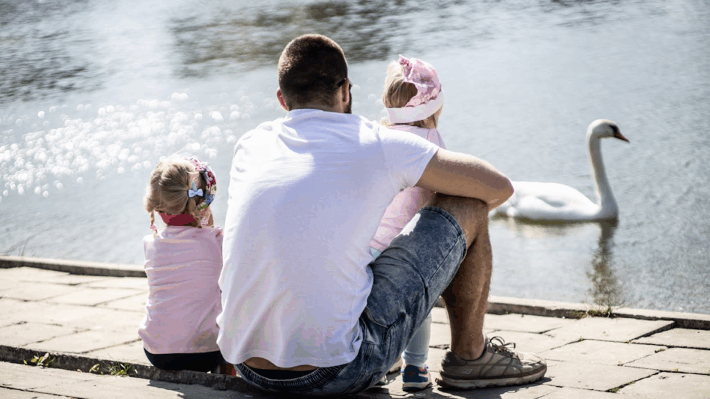 Girl Sitting Next to Man While Holding Baby