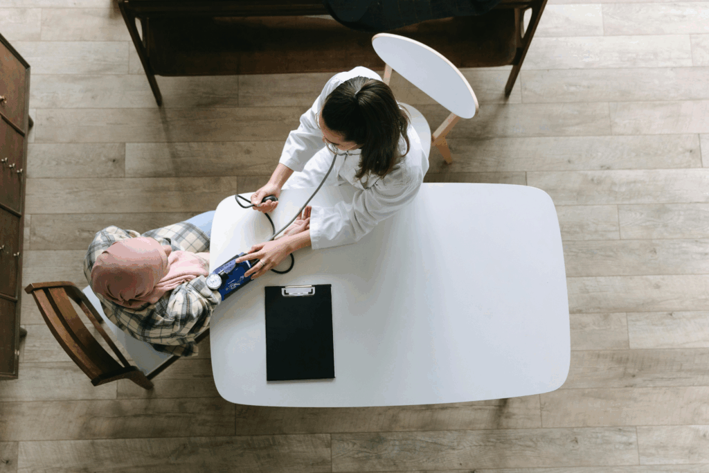 Overhead view of healthcare provider measuring blood pressure of a person during routine checkup, emphasizing the importance of regular screenings to detect rare cancer symptoms early.