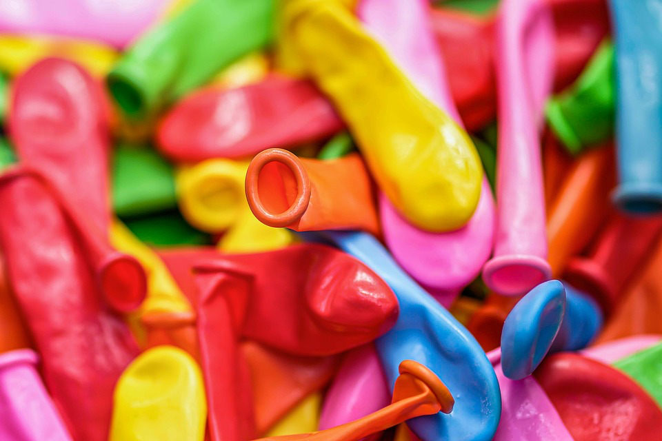 Close-up of colorful uninflated party balloons in vibrant shades of pink, orange, yellow, red, green and blue, representing the safer air-filled alternative that "look just as nice" but don't carry the deadly risks of helium balloons.